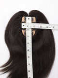 A dark brown to black hair extension piece with a natural-looking base, shown with a measuring tape to indicate its size on a white background.